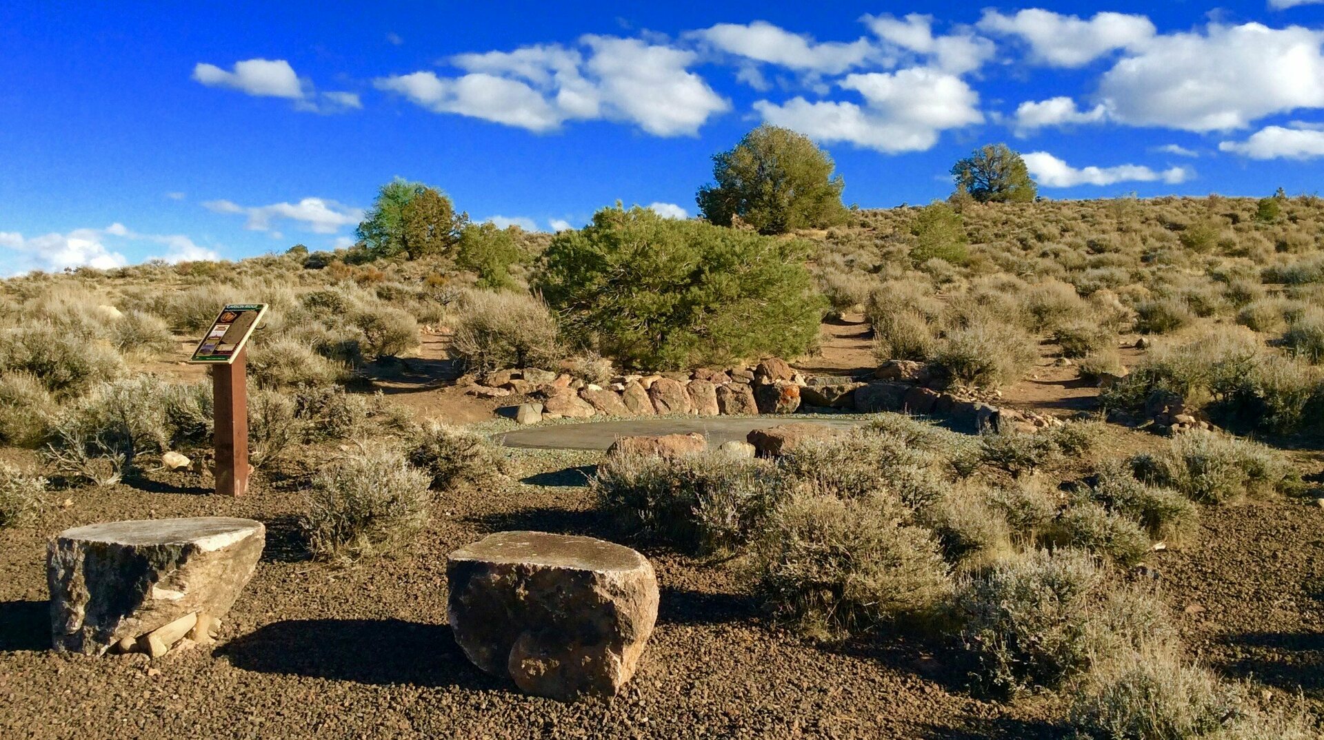 tee area and bench with basket downhill in the distance amid desert landscape
