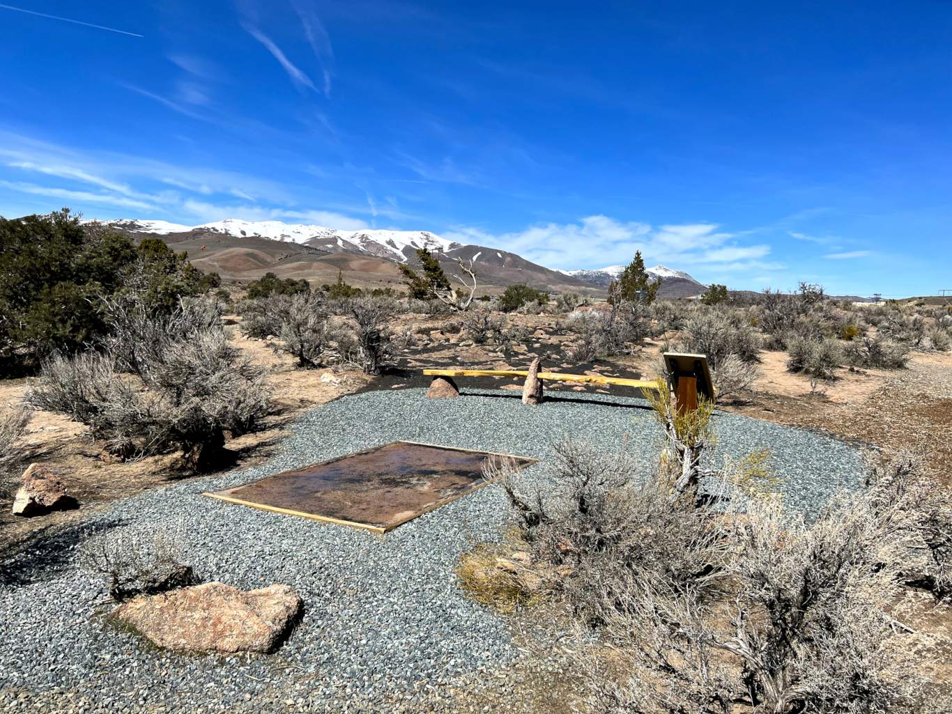 a tee area with bench and landscaped tee area with mountains in background